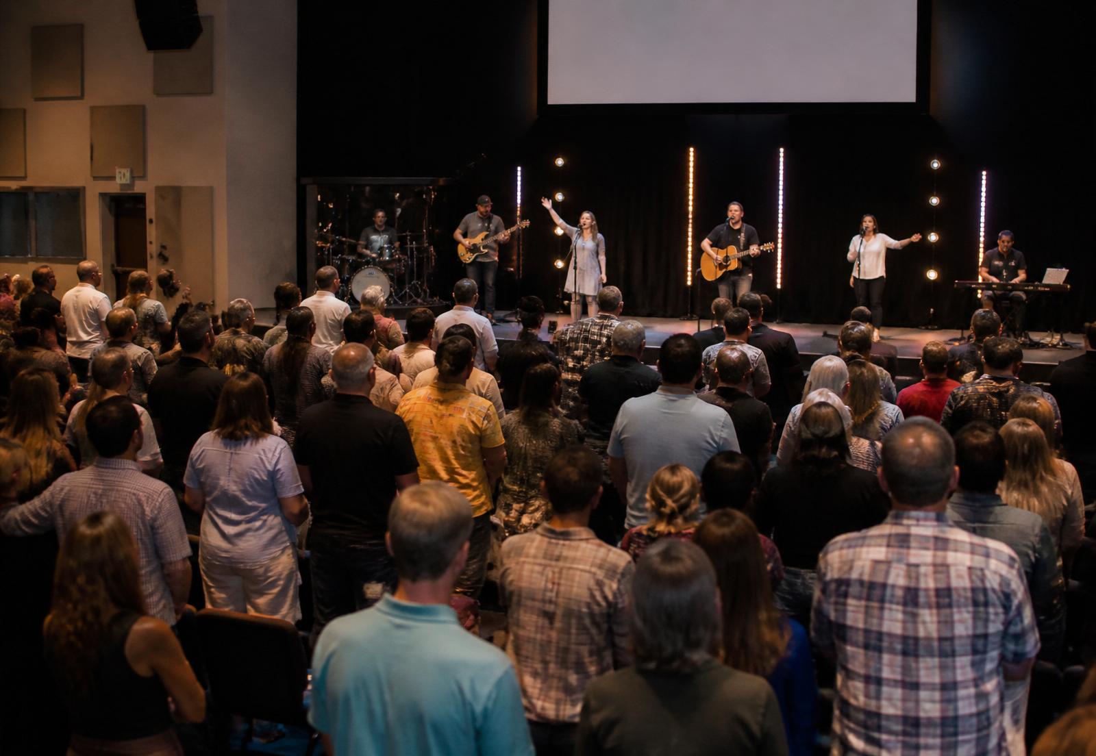 A Pentecostal worship service with a live band and congregation.